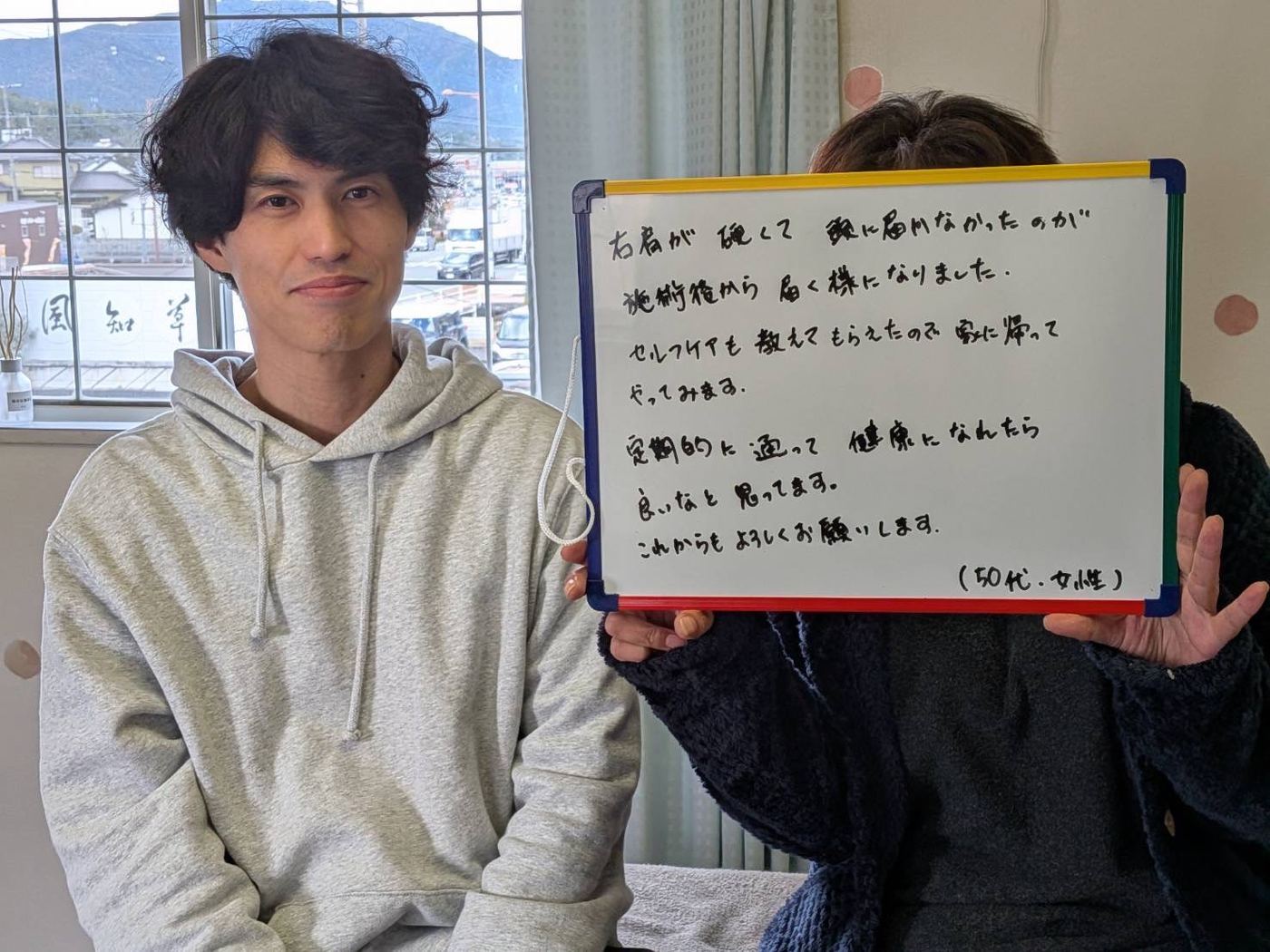 右肩が硬くて腕が上がりにくかった50代女性のお客様と院長。施術後から頭まで手が届くようになったという手書きのメッセージ